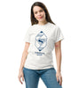 Femme souriante portant un t-shirt blanc Force for Good avec logo Superman 2025 en bleu, design géométrique moderne et stylé.