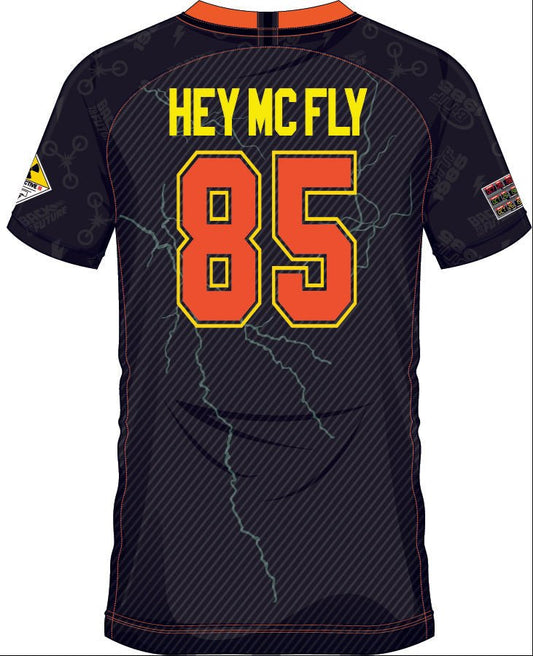 Dos du maillot 'HEY MCFLY 85' Retour vers le Futur avec numéro 85 en orange et jaune, éclairs stylisés et lettrage rétro pour fans de cinéma.