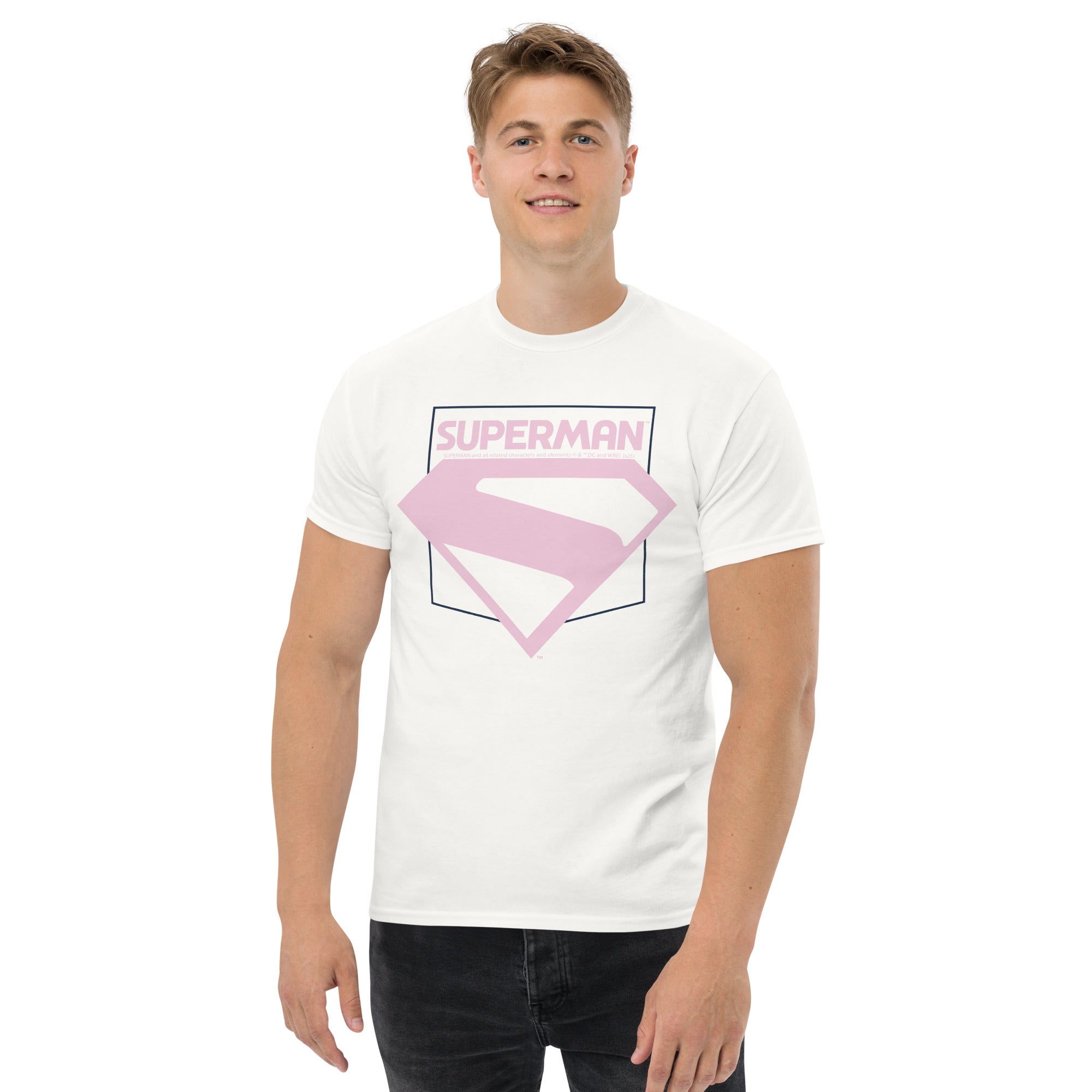 Homme portant un t-shirt blanc Superman avec emblème rose pastel, style inspiré du film Superman 2025, mode urbaine pour fans de DC Comics.